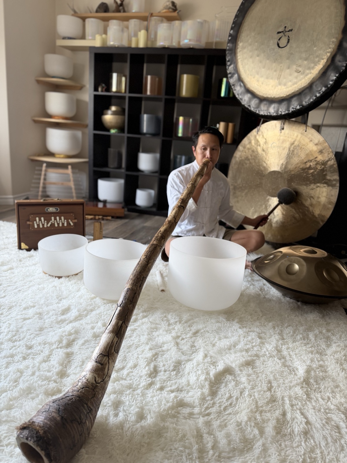 Sound bath and sound healing in Edmonton: Marcus playing didgeridoo among crystal singing bowls, gongs and a handpan