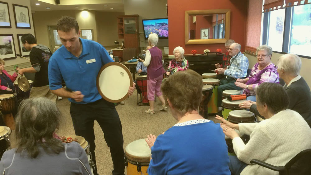 Residents and care staff drumming together in a seniors residence