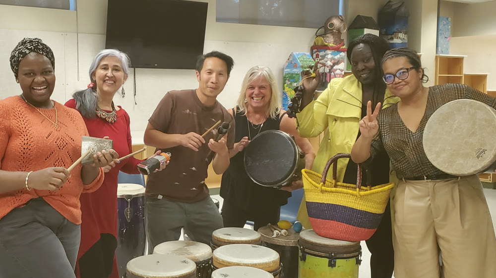 Marcus Fung laughing with Multicultural Health Brokers team members holding drums